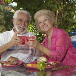 Elderly couple with drinks in garden